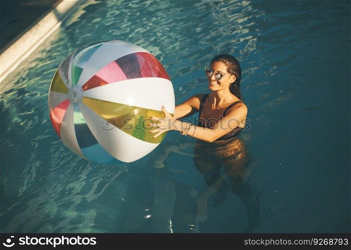 Top view at young woman with ball in the pool at sunny day