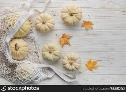 Top view autumn composition with pumpkins in mesh shopping bag on a wooden background