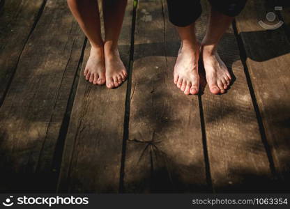 Top view bare feet of male and female couple standing on wooden bridge.. Top view bare feet of male and female couple standing on wooden bridge