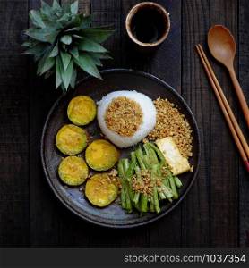 Top view black plate of rice dish for lunch meal, vegan homemade Vietnamese eating, vegetarian food with tofu, grilled vegetables, cowpea, nutrition, delicious and good for health
