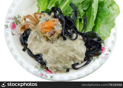 top view black tagliatelle (pasta made with cuttlefish ink) with carbonara sauce , fried crab and fresh vegetable on white background