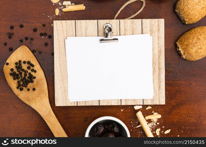 top view blank white paper with clipboard bun bread sticks peppercorn with spatula wooden desk