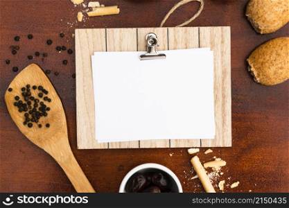 top view blank white paper with clipboard bun bread sticks peppercorn with spatula wooden desk