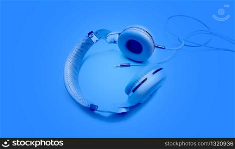 Top view blue headphones and Convention Aux cable 3.5 mm with copy space. Isolated on blue background. White headphones and Convention Aux cable 3.5 mm