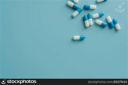 Top view blue-white antibiotic capsule pills on blue background. Prescription drug. Antibiotic drug resistance. Pharmaceutical industry. Pharmaceutical care. Pharmaceutics concept. Antimicrobial drug.