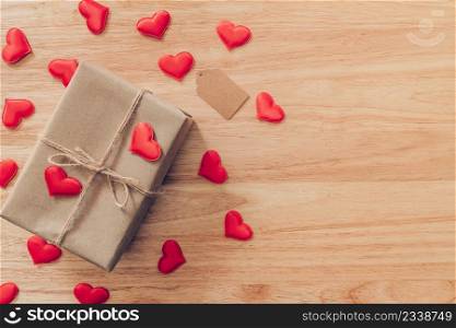 Top view brown gift box and red heart on wood background for valentine day with copy space.