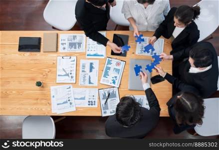 Top view businesspeople and colleagues in formal wear putting jigsaw puzzles together over meeting table with financial report papers in harmony office for team building concept.. Top view businesspeople a putting jigsaw puzzles together in harmony office.