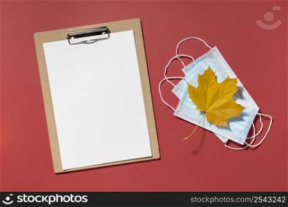 top view clipboard with medical masks autumn leaf