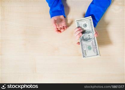Top view, close-up of hands counting money. Happy child with money dollar, little businessman. Pile of United States dollar hundred USD banknotes in boy&rsquo;s hand.. Close-up of hands counting money. Happy child with money dollar, little businessman. Pile of United States dollar hundred USD banknotes