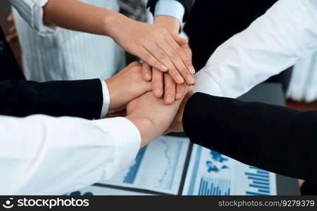 Top view closeup business team of suit-clad businesspeople join hand stack together. Colleague collaborate and work together to promote harmony and teamwork concept in office workplace.