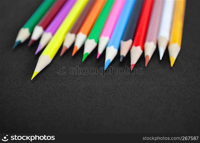 Top view, Closeup of colorful crayon pencils with selective focus on yellow color on matte black background with copy space, Back to school concept, Drawing concept.