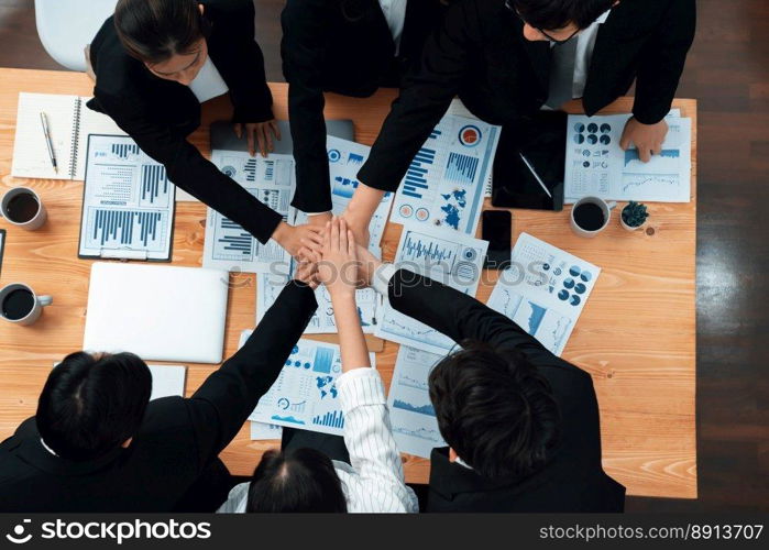 Top view cohesive group of business people join hands together, form circle over table filled with financial report paper. Colleagues working to promote harmony and team building concept in workplace.. Businesspeople join hands together from top view as concept of harmony in office