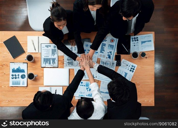 Top view cohesive group of business people join hands together, form circle over table filled with financial report paper. Colleagues working to promote harmony and team building concept in workplace.. Businesspeople join hands together from top view as concept of harmony in office