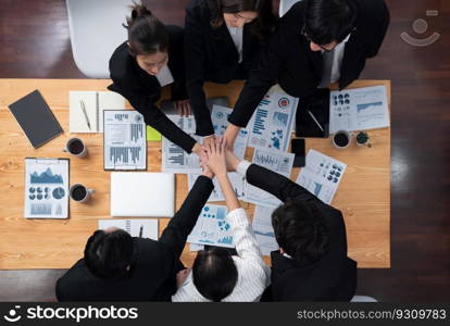 Top view cohesive group of business people join hands together, form circle over table filled with financial report paper. Colleagues working to promote harmony and team building concept in workplace.. Businesspeople join hands together from top view as concept of harmony in office