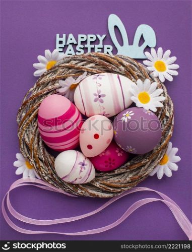 top view colorful easter eggs basket with chamomile flowers