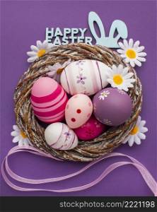 top view colorful easter eggs basket with chamomile flowers