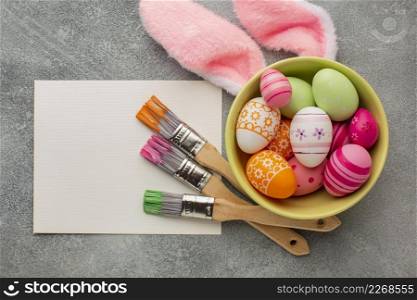 top view colorful easter eggs bowl with paint brushes bunny ears