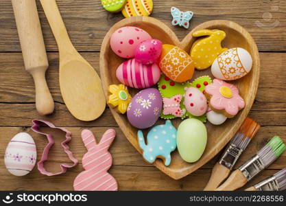 top view colorful easter eggs heart shaped plate with kitchen utensils paint brushes