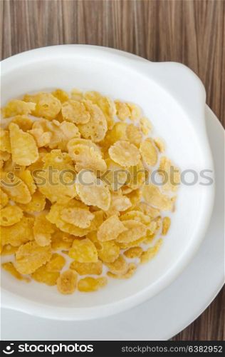 top view corn flake with fresh milk in white bowl . cornflakes