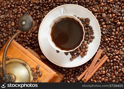top view cup of coffee and roasted coffee beans with retro wood manual mill with cinnamon