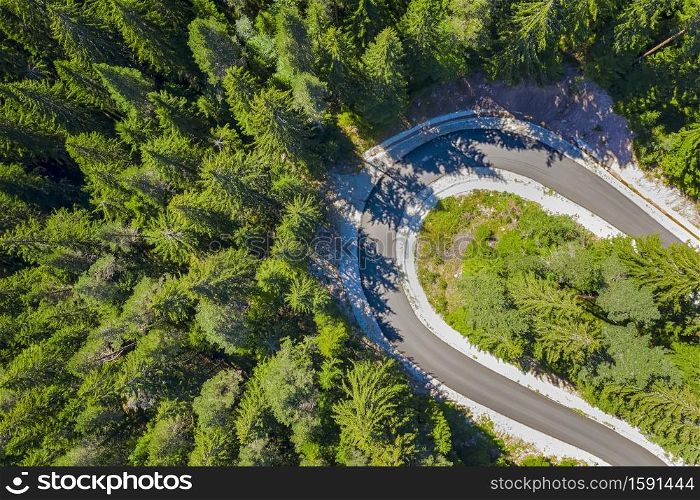 Top view, drone shot of curving forest road in the pine woods in the mountain