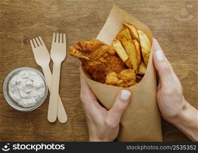 top view fish chips paper wrap held by woman