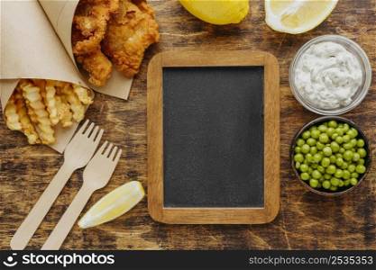 top view fish chips paper wrap with peas chalkboard
