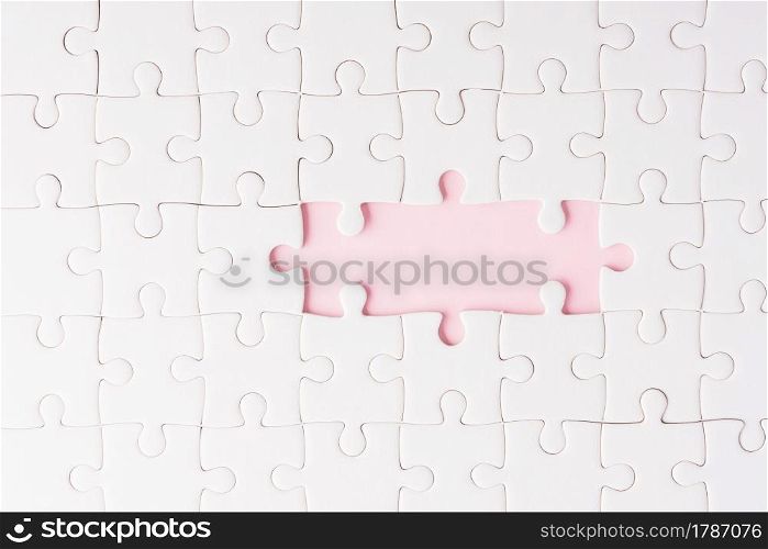 Top view flat lay of paper plain white jigsaw puzzle game texture incomplete or missing piece, studio shot on a pink background, quiz calculation concept