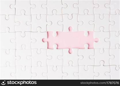 Top view flat lay of paper plain white jigsaw puzzle game texture incomplete or missing piece, studio shot on a pink background, quiz calculation concept