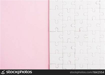 Top view flat lay of paper plain white jigsaw puzzle game texture on a pink background, quiz calculation concept