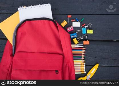 Top view flat lay of red school bag backpack and accessories tools for children education on black wood background, Back to school concept and have copy space for use