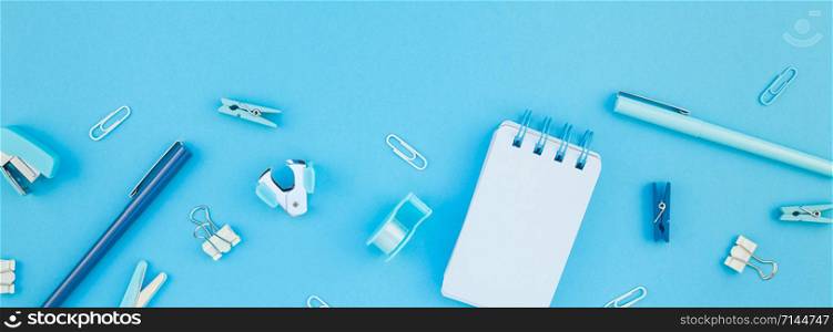 Top view flat lay of workspace desk styled design school and office supplies with copy space turquoise blue color paper background minimal style. Long wide banner Template feminine blog social media