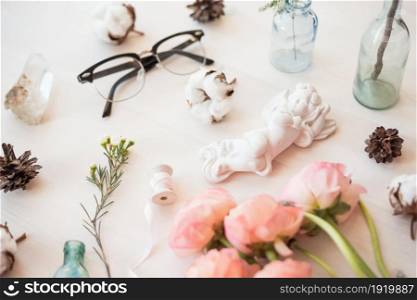 Top view flat lay photo of a scene with flowers, and angel decor element, jars and bottles.. Cute vintage mock up on wooden background. Flat lay top view.