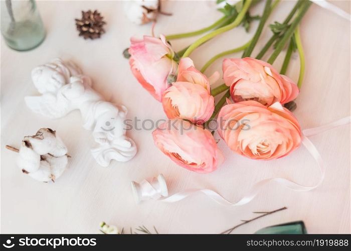 Top view flat lay photo of a scene with flowers, and angel decor element, jars and bottles.. Cute vintage mock up on wooden background. Flat lay top view.