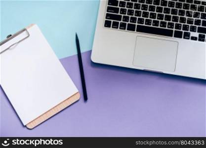 Top view flat lay style of worksapce desk with laptop and blank clipboard on minimal color background
