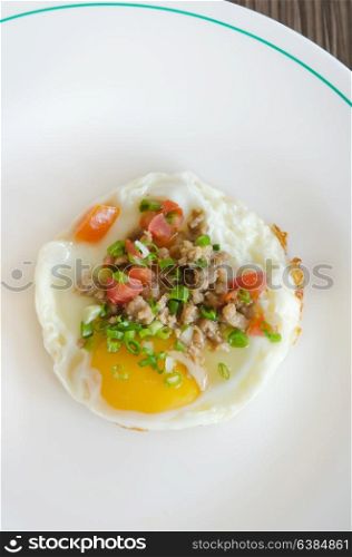 top view fried egg with minced pork and vegetable on white dish. egg and pork