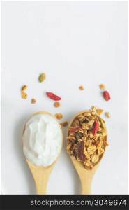top view granola and yogurt in wooden spoons on white background, vertical idea for banner with copy space