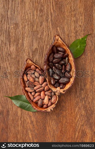 Top view halves of cocoa tree pods filled with piles of peeled and unpeeled beans on wooden surface. Pods with organic cocoa beans