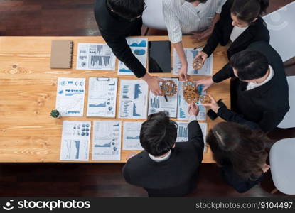 Top view hand holding gear by businesspeople wearing suit for harmony synergy in office workplace concept. Group of people hand making chain of gears into collective form with dashboard report papers.. Top view hand holding gear by group of businesspeople on table in harmony office