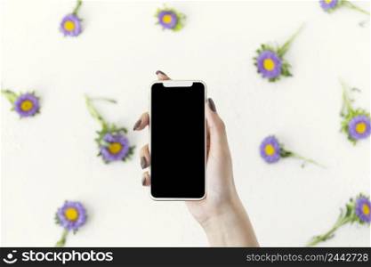top view hand holding phone surrounded by flowers