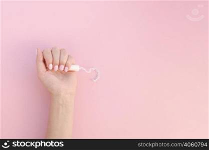 top view hand holding tampon pink background