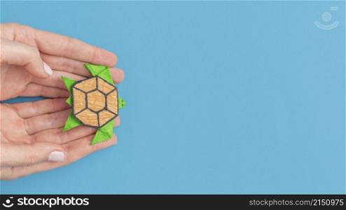 top view hands holding paper turtle with copy space animal day