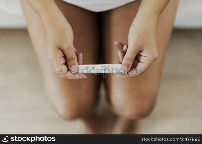 top view hands holding positive pregnancy test