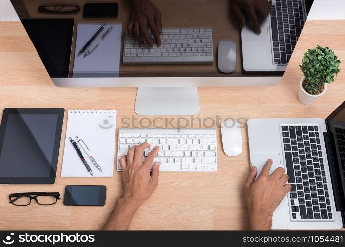 Top view hands of people working with computer PC and laptop with digital tablet and smartphone on wooden desk workspace