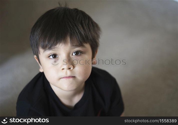 Top view head shot kid looking up with copy space, Candid young boy looking at camera with curiouse face, Child sitting on floor relaxing at home on weekend, Healthy and Positive children concept