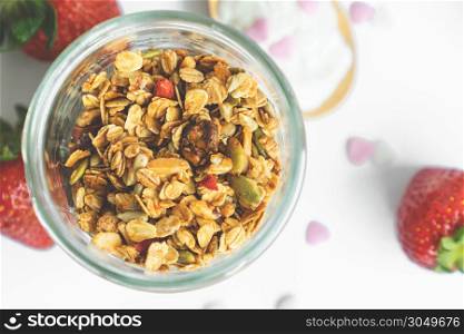 top view healthy granola in glass clear bottle with copy space and fresh strawberry in background