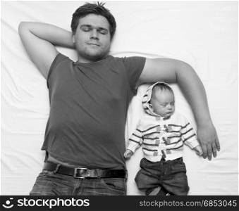 Top view image of father and baby boy sleeping on bed