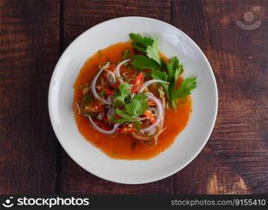 Top view image the Spicy salad of sardine with tomato sauce in white dish on wooden table, mixed with herb and lemonade, copy space