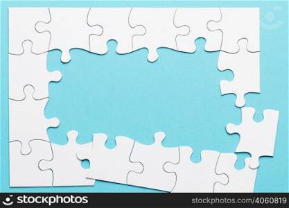 top view incomplete puzzle frame blue backdrop