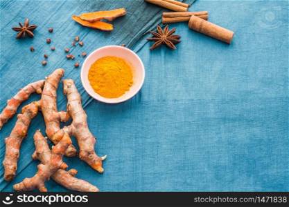 Top view ingredients dried spices with copy space on bright blue background. Organic turmeric curcumin fresh roots and powder, cinnamon and star anise to make natural herbal drink and healthy food